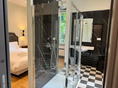 a shower with a glass door in a bedroom at Santa Monica Townhouse in Rome