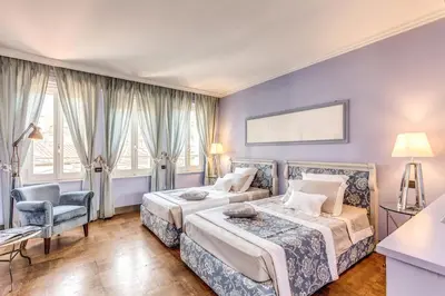 a bedroom with two beds and a chair at Hotel Villa Linneo in Rome