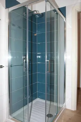 a glass shower in a bathroom with blue tiles at La Romàntìca al Colosseo in Rome