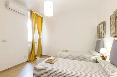two beds in a room with yellow curtains at La Romàntìca al Colosseo in Rome