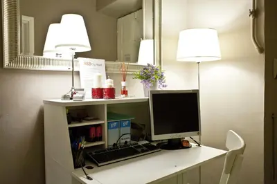 a desk with a computer and two lights and a mirror at Happy Stay Guesthouse in Rome
