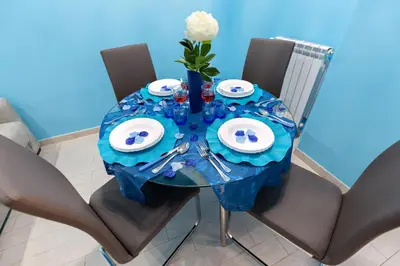 a dining table with a blue table cloth and a white rose at Louise at Colosseum in Rome