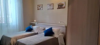two beds in a hotel room with blue pillows at Vatican View Rooms in Rome
