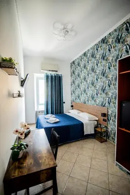 a bedroom with a blue bed and a table at Hotel Dell'Urbe in Rome