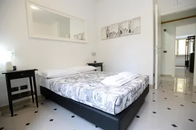 a white bedroom with a bed and a table at Casa Andrew in Rome