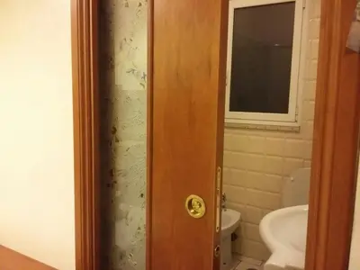 a bathroom with a toilet and a window and a door at Monolocale Monteverde in Rome