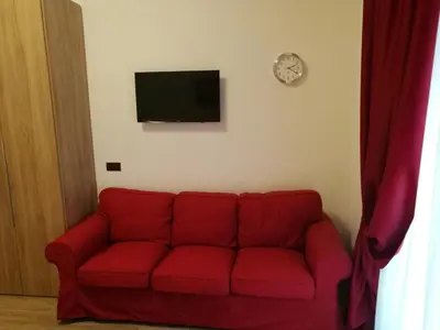 a red couch in a living room with a clock at Al Trenino accomodation in Rome