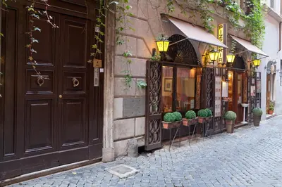 a cobblestone street in front of a building with a store at Baldassini Suites in Rome