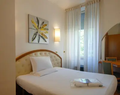 a bedroom with a bed with a white bedspread and a window at Hotel Regina Margherita in Rome