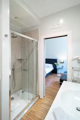 a bathroom with a glass shower and a bedroom at At Home Townhouse - Filiberto in Rome