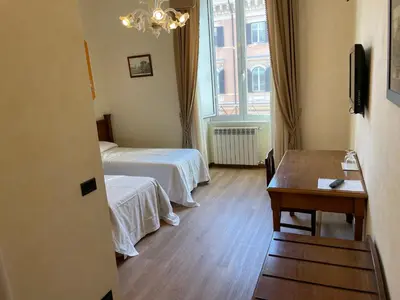 a hotel room with two beds and a table at Le Petit Real in Rome