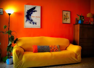 a yellow couch in a room with an orange wall at 4321 B&B Stazione Trastevere in Rome