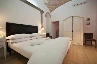 a bedroom with a large white bed with a black headboard at B&B La finestra sul Colosseo in Rome