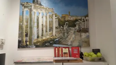 a painting hanging on a wall with books on a shelf at Hotel Louisiana in Rome