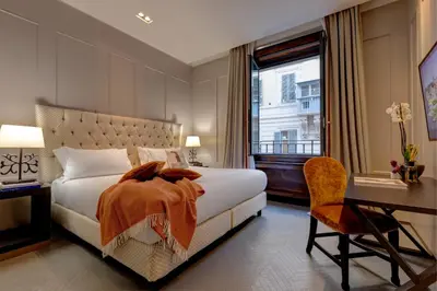 a bedroom with a bed and a desk and a window at Singer Palace Hotel Roma in Rome