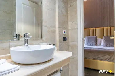a bathroom with a white sink and a bed at Via Veneto Suites in Rome