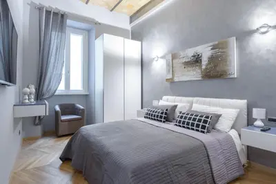a bedroom with a large bed and a chair at Sylvia Stylish Vatican Apartment in Rome