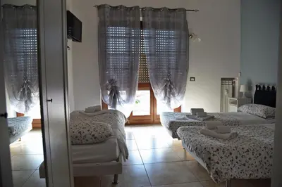 a room with three beds and a window with curtains at Marco E Laura Affittacamere al Vaticano in Rome