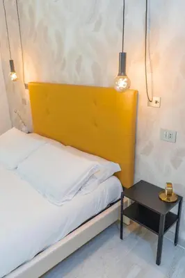 a bed with a yellow headboard next to a table at iRooms - Spanish Steps in Rome