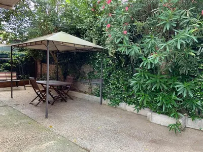a table and chairs under an umbrella next to a bush at Appia Park apartament 10 min dal Colosseo in Rome