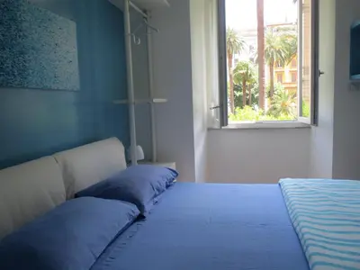 a bed with blue pillows in a room with a window at WellnessINNrome shortlet in Rome
