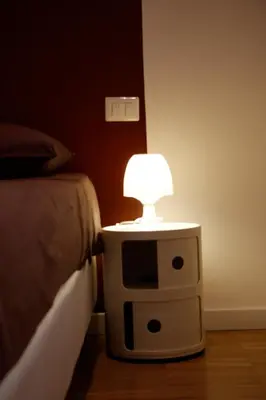 a nightstand with a lamp on it next to a bed at WellnessINNrome shortlet in Rome