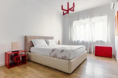 a white bedroom with a bed and a red night stand at Apartment Costanza in Rome in Rome