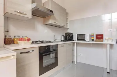 a kitchen with white cabinets and a stove top oven at Claudia House Roma Termini in Rome