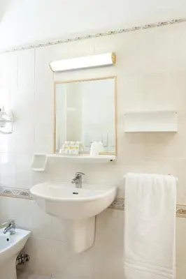 a white bathroom with a sink and a mirror at Hotel Santa Prisca in Rome