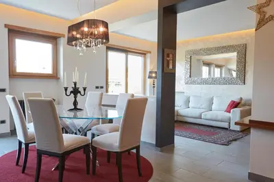 a dining room with a glass table and white chairs at Vatican Luxury Penthouse with Terrace in Rome
