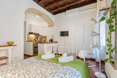 a bedroom with a large bed and a kitchen at Enchanting loft in Trastevere in Rome