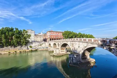 a bridge over a river with buildings in the background at Enchanting loft in Trastevere in Rome
