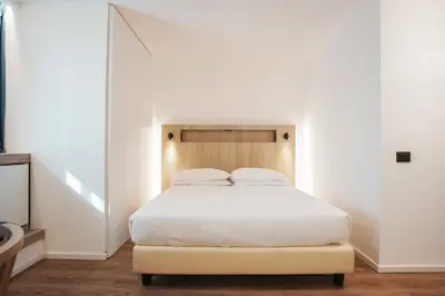 a bedroom with a white bed with a wooden headboard at Aparthotel Colombo Roma in Rome