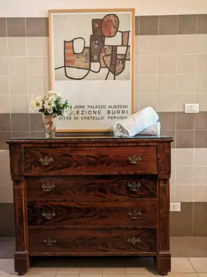 a dresser with a vase of flowers on top of it at Penna Apartment in Rome