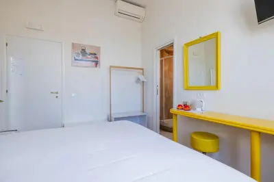 a bedroom with a white bed and a yellow mirror at Superior Relais FCollection Temple View in Rome