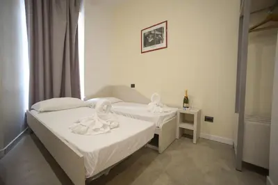 a room with two beds and a table with a bottle of wine at Romerooms in Rome