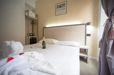 a bedroom with a white bed with a bottle of wine on it at Romerooms in Rome