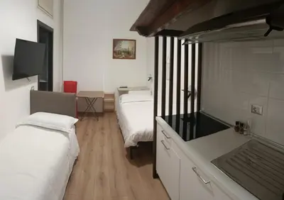 a room with two beds and a kitchen with a tv at Principe Guesthouse in Rome