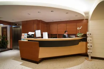 a woman standing at a reception desk in a lobby at Hotel Memphis in Rome