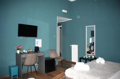 a blue room with two beds and a desk and a tv at My Rhome Prati in Rome