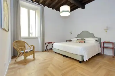 a white bedroom with a bed and a chair at Residenza Torre Vecchiarelli - apt 3 in Rome