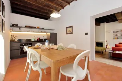 a kitchen and dining room with a wooden table and white chairs at Residenza Torre Vecchiarelli - apt 3 in Rome