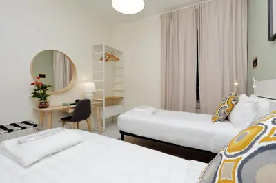 a hotel room with two beds and a desk and a mirror at Casa Santa Sofia in Rome