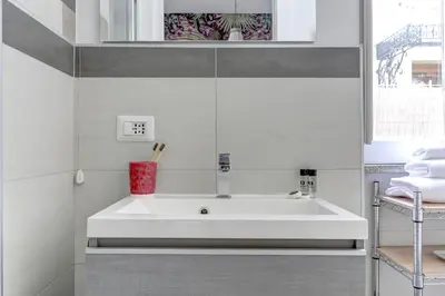 a bathroom with a white sink and a mirror at Colosseo Secret Garden - Home and More in Rome