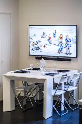 a white table with chairs and a tv on the wall at Balestra Palace Apartment in Rome