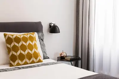 a bedroom with a bed with a yellow pillow and a lamp at Maison Letizia Roma in Rome