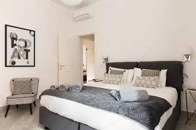 a bedroom with a large bed and a chair at Maison Letizia Roma in Rome