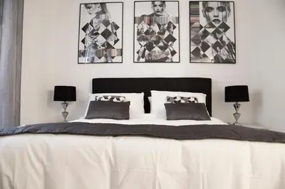 a bedroom with a large white bed with four pictures on the wall at Argentina Exclusive Apartment in Rome