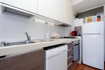 a white kitchen with a sink and a refrigerator at Dolce Casa Colosseo in Rome