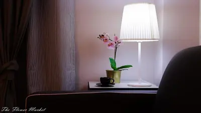 a table with a lamp and a vase with flowers on it at The Flower Market Apartment in Rome